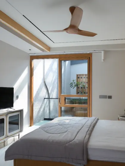 The master bedroom on the third level of the Slender House is minimalist in design, with clean-lined furniture and modest elegance. Natural light from the skylight brightens the room, which is connected to other spaces via a glass corridor.