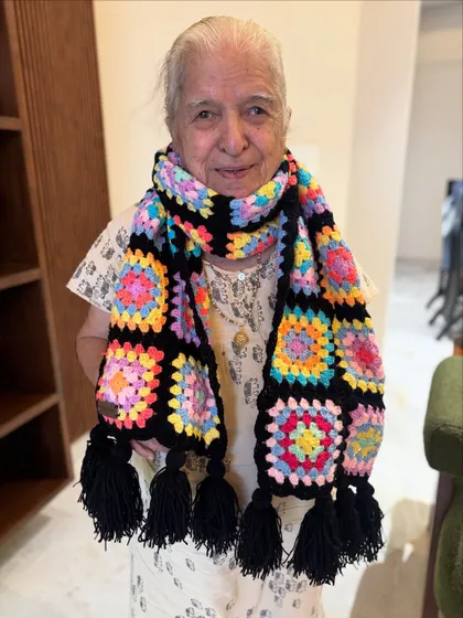 Dadi is all smiles showing off this vibrant granny square muffler. Made with soft 4-ply yarn and finished with playful tassels, it’s designed to keep you warm while adding a pop of cheerful color to your winter wardrobe.