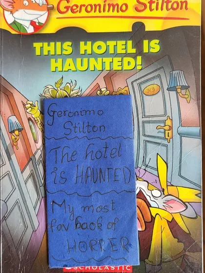 The book "This Hotel is Haunted" with the secret note tucked inside. It’s like a treasure hunt within the library!