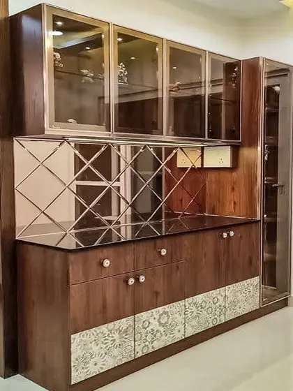 A luxurious crockery unit design featuring dark wood, a diamond-patterned mirror backsplash, and glass-front cabinets. This piece adds both storage and glamour to a dining area.