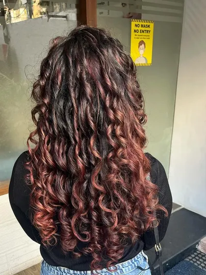 Burgundy pintura highlights for Manali’s curls, styled with Manetain products.