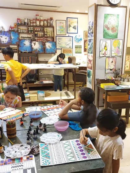 The studio is alive with color and concentration. Young artists are deeply engrossed in their pattern-making projects, using a variety of materials to explore different artistic styles.