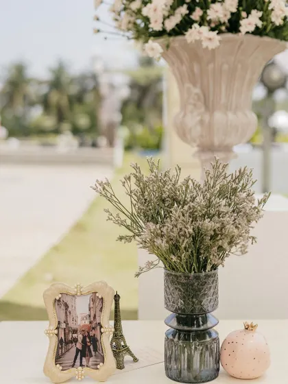 A collection of props on a table, including a framed photo, Eiffel Tower, and dried flowers.