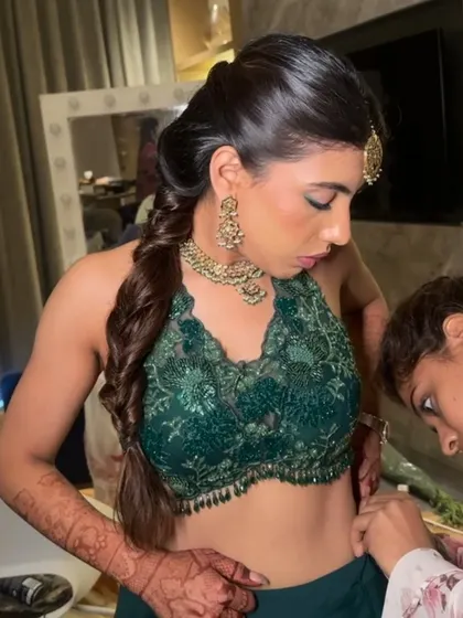 A behind the scenes moment, showing the final touches on a modern fishtail braid for a Sangeet.
