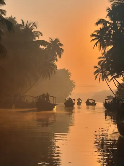The silhouette of boats and coconut trees against the morning sun.