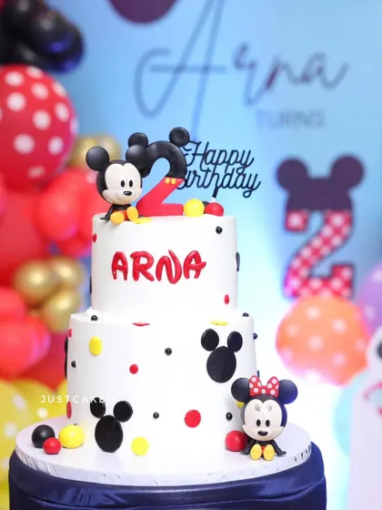 This two-tiered Mickey and Minnie Mouse cake was the star of a second birthday party. It features cute, hand-sculpted edible figures and a classic polka-dot design.