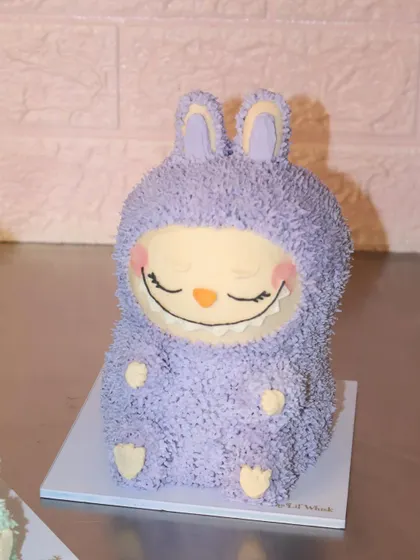 We are obsessed with this sleepy, smiling purple Labubu cake. Every detail, from the fuzzy ears to the tiny feet, is sculpted from delicious buttercream.