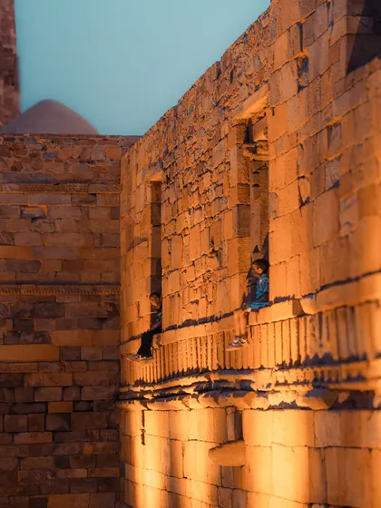 Children sitting in the windows of the ancient structures at the Qutub Minar complex. A moment where the past and present meet.