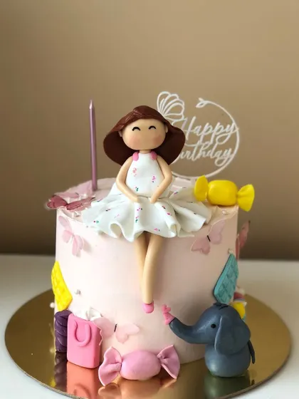 A sweet cake with a doll topper, surrounded by her favorite things.