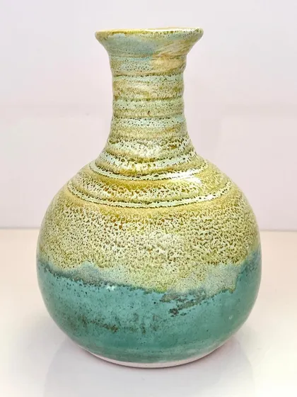 This vase, named "Coral Coast," features a beautiful textured glaze that transitions from a sandy yellow-green to a soft aqua blue.