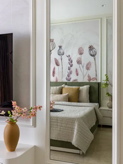A reflection in the mirror shows the serene sage green bedroom, highlighting the custom wallpaper and the calm, sophisticated ambiance of the space.