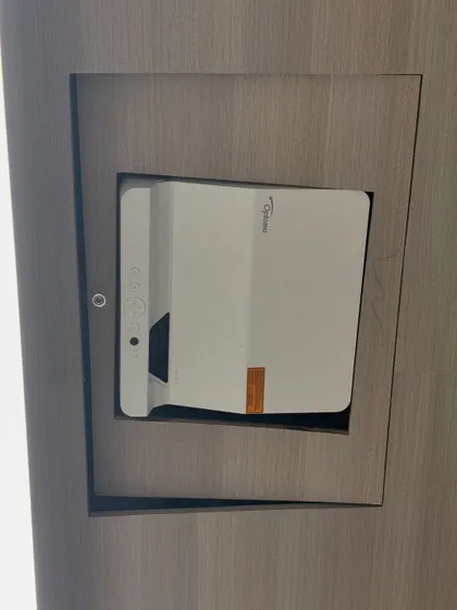 A close-up of the custom-built niche housing the Optoma AZH430UST projector. This clean installation keeps the hardware out of the way, preventing clutter on the conference table and protecting the equipment.