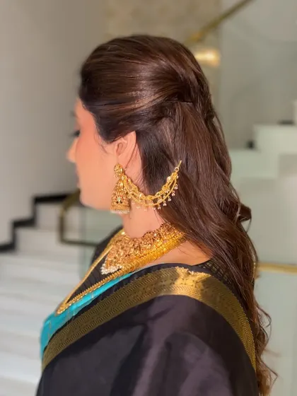 A side profile showing the flow of the hair and the neatness of the saree pallu. This combination of classic saree with modern hair is very popular for receptions.