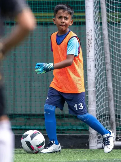 A young goalkeeper focused during a Pro Super League match. We train our keepers to be confident and commanding from an early age.