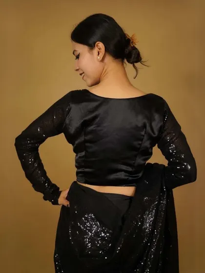 The back of this black satin blouse with sequined sleeves is simple yet alluring. It’s designed to be both comfortable and glamorous for a night out.