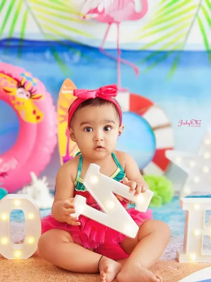 Celebrating turning one with a fun beach party theme. The light-up letters and flamingo prop add to the festive, tropical vibe.