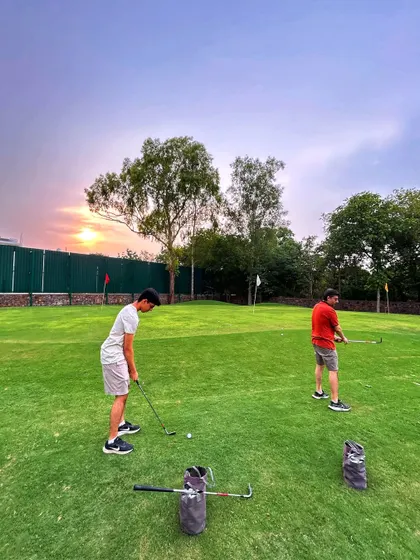 Two friends practice their putting as the sun sets. A perfect end to a weekend day.
