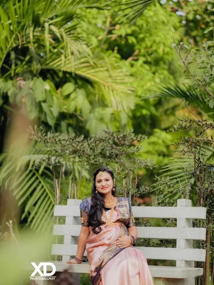 A peaceful portrait of the mother-to-be seated on a bench in a garden, surrounded by nature.