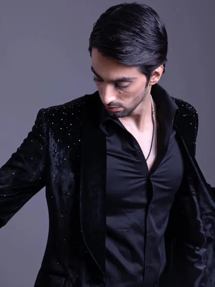 A different angle of the embellished black velvet jacket, showing how it drapes and moves. It's a piece designed for a dapper, elegant look.