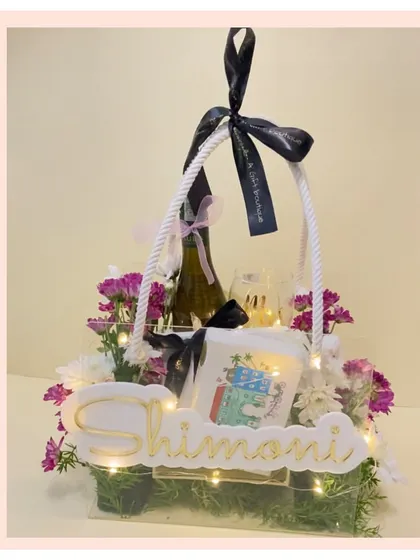 A customized acrylic basket hamper with a floral arrangement and fairy lights. The personalized nameplate makes this a truly special and modern gift.