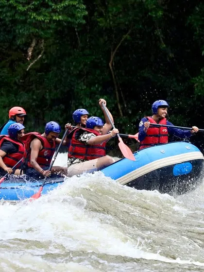 An expert guide steers from the back of the raft, navigating a team through the turbulent waters of the Barapole River. Safety and expert guidance are the cornerstones of all our expeditions.
