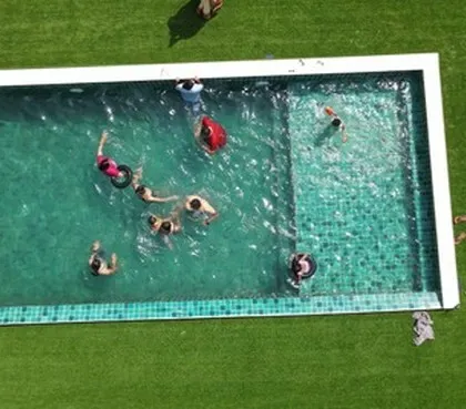 An aerial view of guests enjoying the private pool at Panorama Peaks, Coorg, surrounded by a lush green lawn.