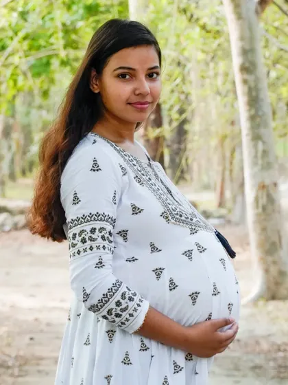 A lovely portrait of an expectant mother in a white dress, enjoying a moment in the park. We use natural settings to create a relaxed and beautiful backdrop.