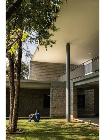 A person enjoying the tranquility of the green space, sheltered by the building's cantilevered roof.