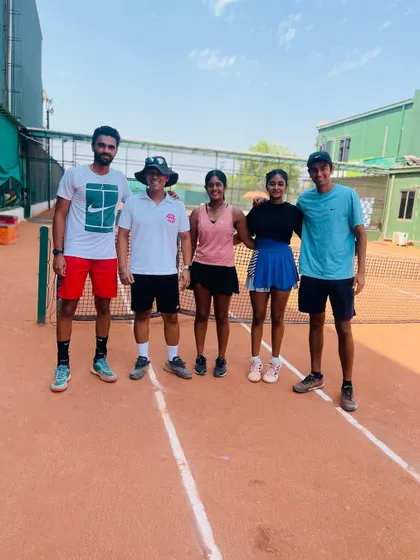 The team takes a moment to celebrate their collective success. This photo shows our players and coach on the clay courts after a great week of tennis in Ahmedabad.