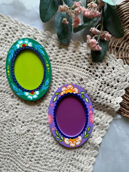 A pair of oval photo frame magnets, each with a unique floral design.