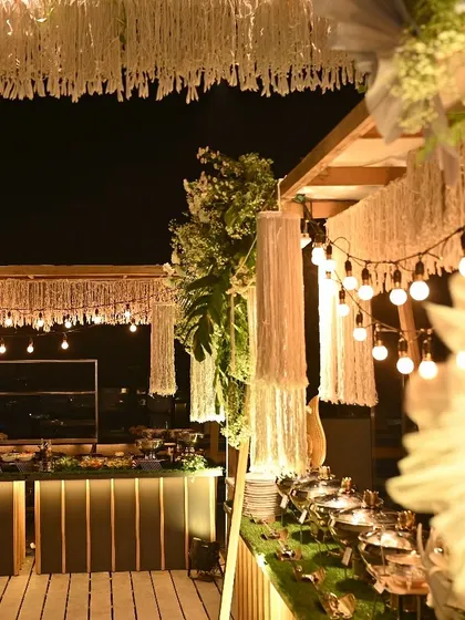 The stunning outdoor buffet and live station setup for a large anniversary party, with beautiful macrame and string light decor.