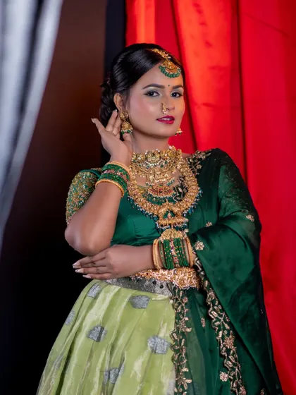 A classic portrait pose, the model's expression complements the elegance of the green outfit and gold jewellery.