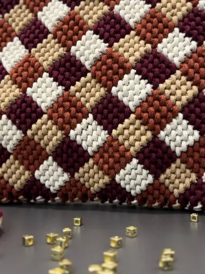 A macro shot showing the incredible detail and precision of the knotting in this checkered bag.