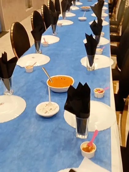 A long view of our formal dining setup. The striking blue and black theme, with neatly folded napkins and pre-set dishes, shows our ability to execute a sophisticated and large-scale seated dinner service.