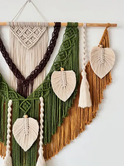 A closer look at the details in this earthy-toned wall hanging. You can see the different knotting techniques used to create texture, from the braided sections to the delicate macrame leaves.