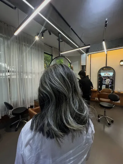 A full view of the salon with the client showcasing her new silver highlights. It gives a great sense of the final look in our space.