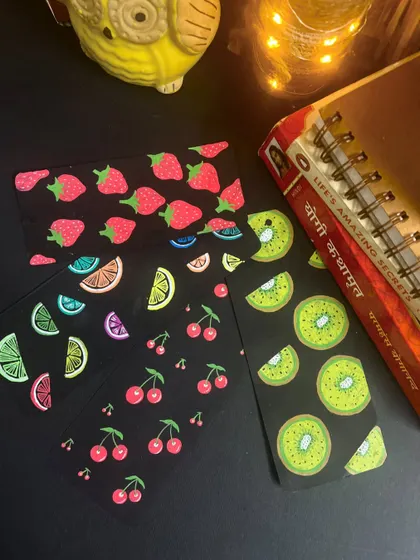 A set of fruity bookmarks featuring strawberries, kiwis, lemons, and cherries. These fun doodles on black paper make reading even more enjoyable.