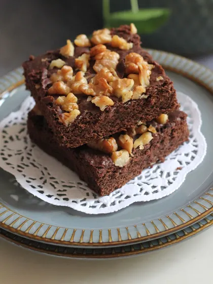 A stack of fudgy walnut brownies. We teach you the secrets to achieving that perfect chewy texture and crinkle top, without using eggs.