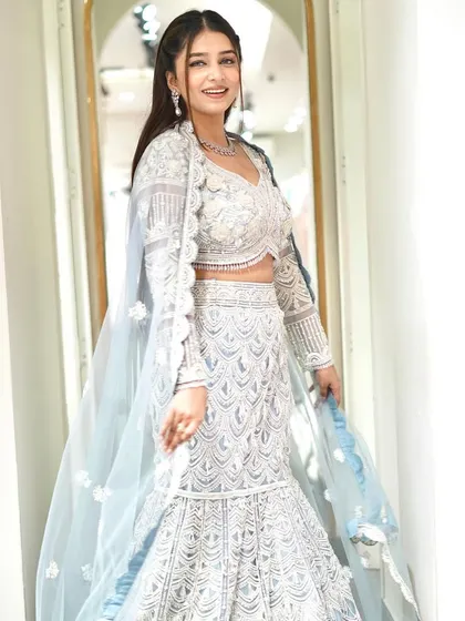 A full, smiling shot of the white and silver fish-cut lehenga. The attached jacket-style dupatta adds a layer of elegance to this modern silhouette.