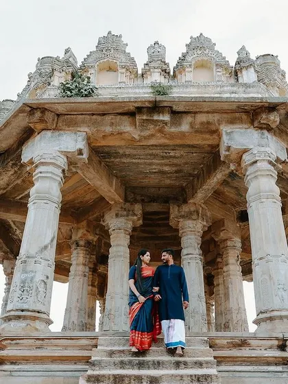 A romantic shot of the couple on the steps of the Melkote temple. The low angle and grand architecture create a sense of timelessness and destiny.