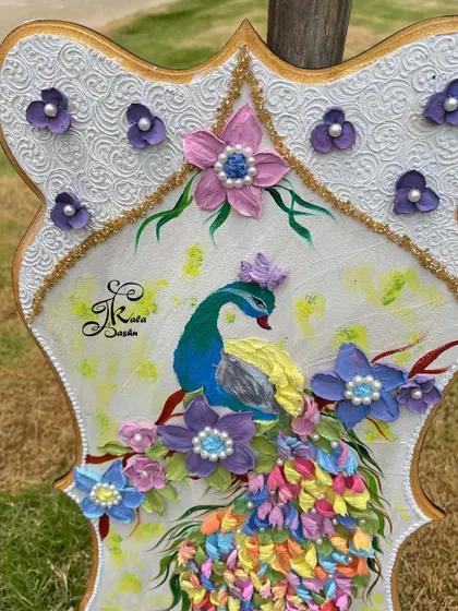 A close-up of a peacock sculpture, focusing on the pearl-centered flowers and the intricate texture of the white border.