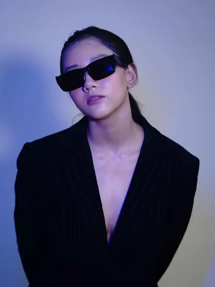 The direct gaze in this blue-lit shot is captivating. It combines the cool, modern aesthetic of the colored light with the powerful presence of the model.