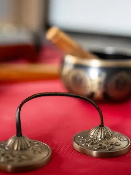 The tools for sound healing laid out on a yoga mat. Tibetan cymbals (Tingsha) and a singing bowl await the start of a session, promising an immersive journey into vibrational therapy and deep relaxation.
