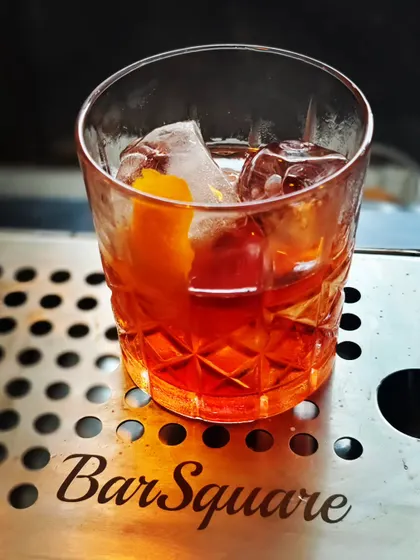 The iconic Negroni, perfectly chilled and served over a large ice cube with an orange peel garnish. I teach how to master classics like this, focusing on the precise balance of gin, vermouth, and Campari.