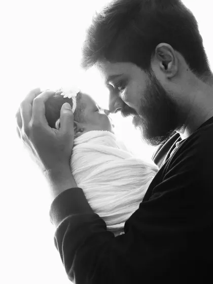 A tender moment between father and child. The high-contrast lighting creates a beautiful silhouette effect, emphasizing the bond between them.
