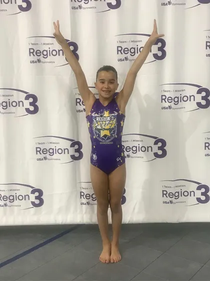 A Diamond level gymnast waves to the crowd at the regional championships.