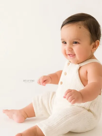 A simple and sweet portrait of a sitting baby. The clean white background puts all the focus on his happy expression and adorable pose.