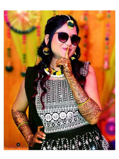 A stylish bride posing with sunglasses during her Mehndi function, adding a modern twist to a traditional event.
