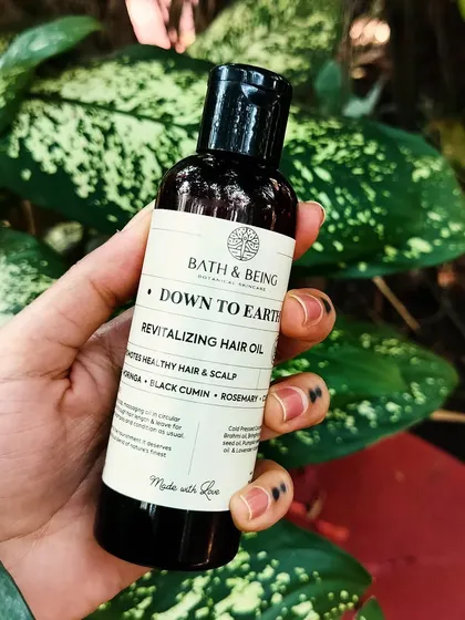 Our Down to Earth Revitalizing Hair Oil is a potent blend of more than 10 cold-pressed oils, including moringa, black cumin, and brahmi. It helps reduce hair fall, tackles scalp issues, and promotes growth.