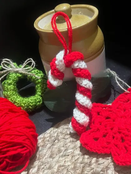 A still shot of the finished candy cane ornament, alongside a mini wreath and other festive creations. These reusable decorations are both eco-friendly and adorable.